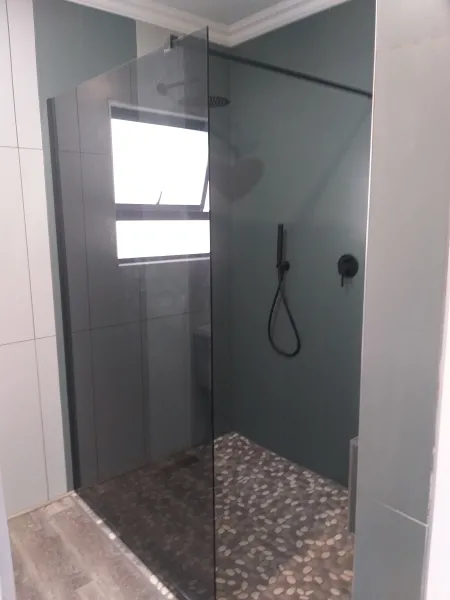 Smoked glass shower screen, pebble mosaic floor, black mixer & rose 
